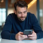 Un homme dans la trentaine examine un smartphone pliable dernière génération dans un bureau moderne, illustrant les innovations technologiques de 2024